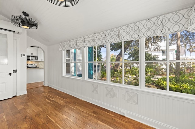 unfurnished sunroom with arched walkways and vaulted ceiling