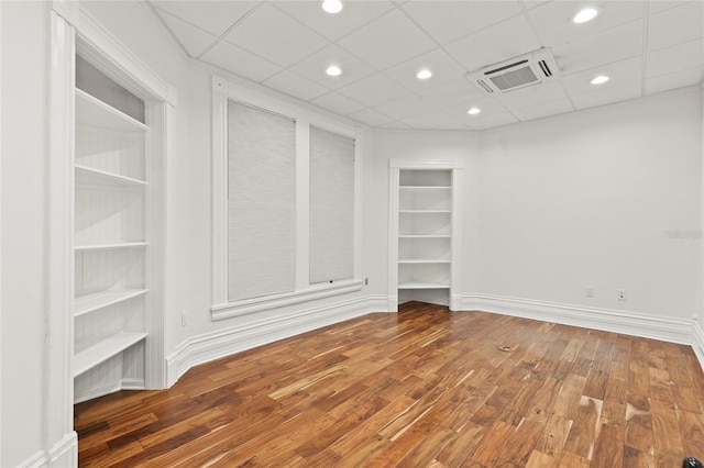 unfurnished room featuring built in shelves, recessed lighting, visible vents, wood finished floors, and baseboards