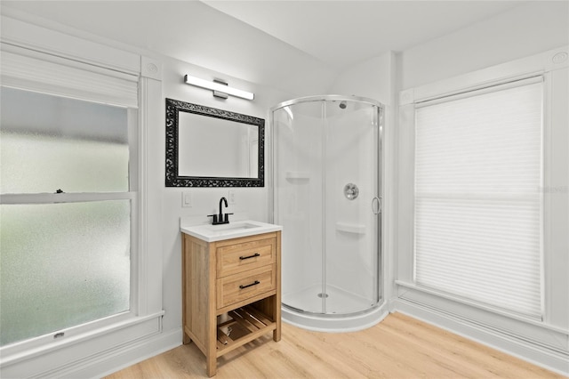 bathroom with a stall shower, vanity, and wood finished floors