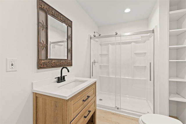 bathroom with a stall shower, vanity, toilet, and wood finished floors