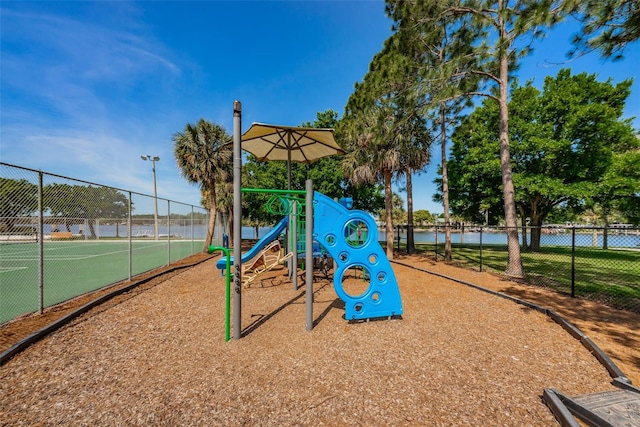 community play area with a tennis court, a water view, and fence