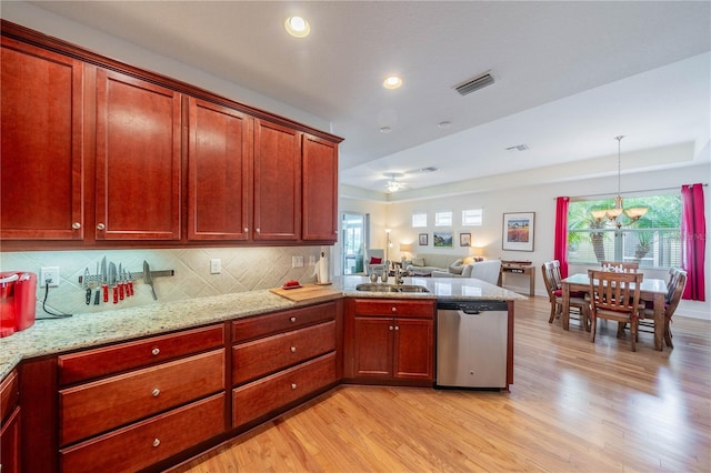 kitchen with visible vents, hanging light fixtures, stainless steel dishwasher, open floor plan, and a sink