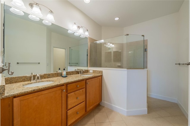 full bathroom featuring double vanity, a stall shower, a sink, tile patterned flooring, and baseboards