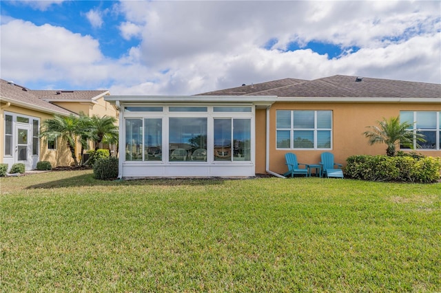 back of house featuring a sunroom, stucco siding, and a yard