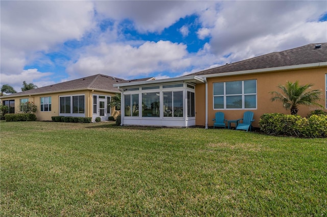 back of property with a yard, a sunroom, and stucco siding