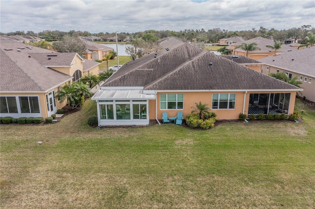 back of house with a shingled roof, a lawn, a residential view, and a sunroom