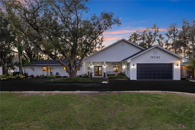 view of front of property with aphalt driveway, french doors, a front yard, a garage, and ceiling fan