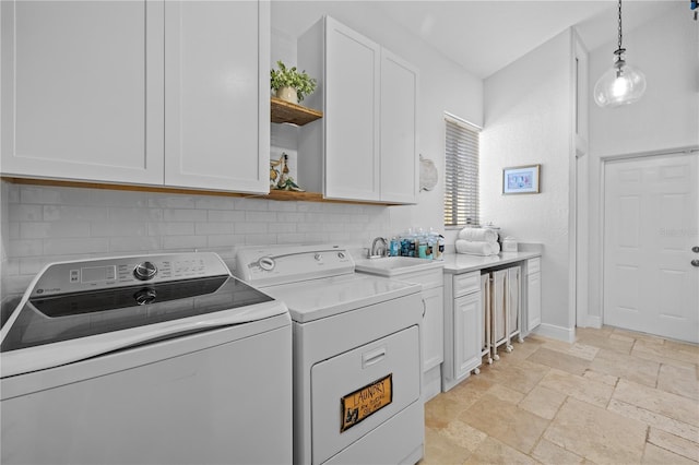 washroom featuring baseboards, cabinet space, a sink, stone tile flooring, and independent washer and dryer