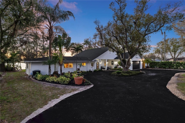 view of front of property featuring a garage, central AC, aphalt driveway, and stucco siding