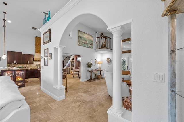 living room with arched walkways, stairway, ornate columns, and a towering ceiling