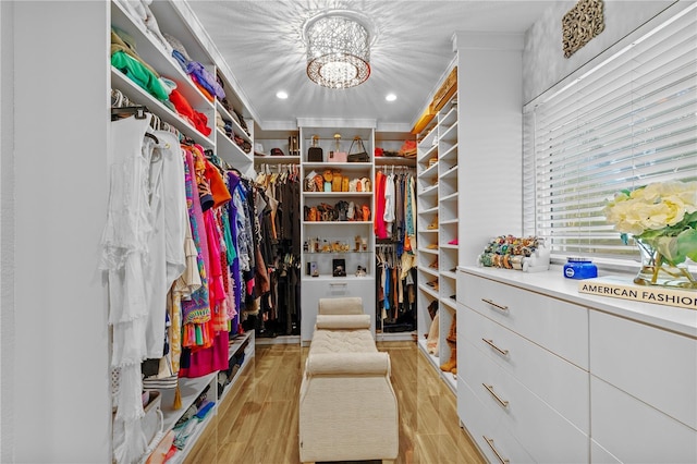 walk in closet with an inviting chandelier and light wood-style flooring