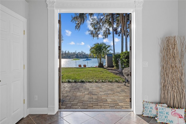 doorway with tile patterned flooring, baseboards, and a water view