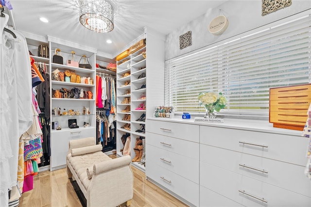 walk in closet featuring a notable chandelier and light wood-type flooring