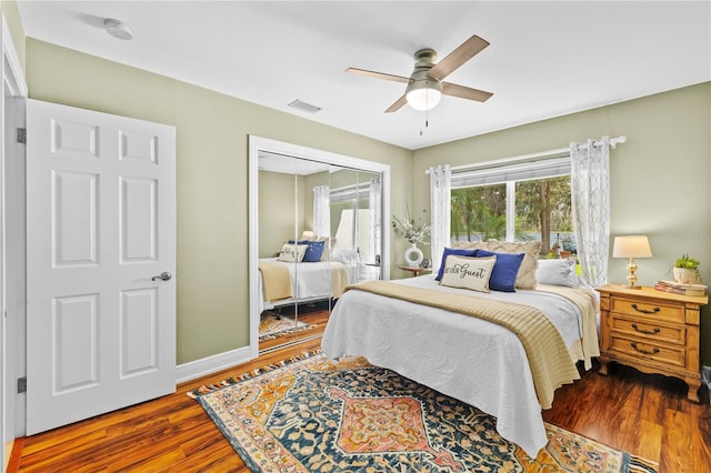 bedroom with visible vents, wood finished floors, a closet, baseboards, and ceiling fan