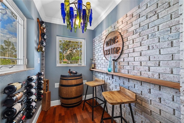 wine area with wood finished floors, a healthy amount of sunlight, baseboards, and ornamental molding