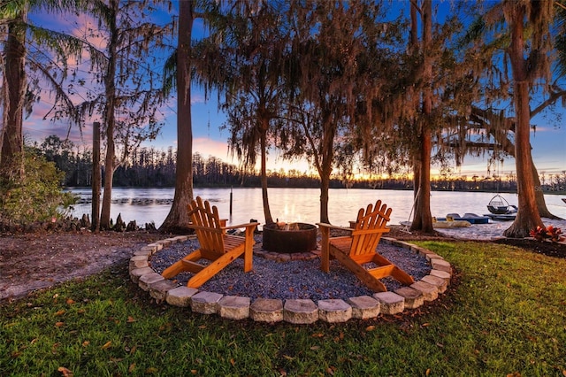 yard at dusk with a fire pit and a water view