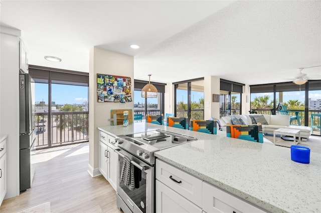 kitchen with appliances with stainless steel finishes, expansive windows, white cabinets, and light stone countertops