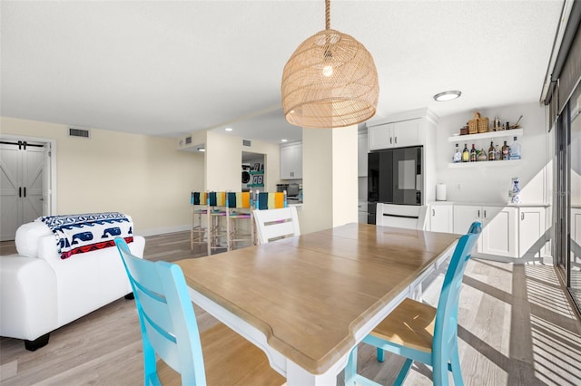 dining space featuring light wood-style floors, recessed lighting, visible vents, and a textured ceiling