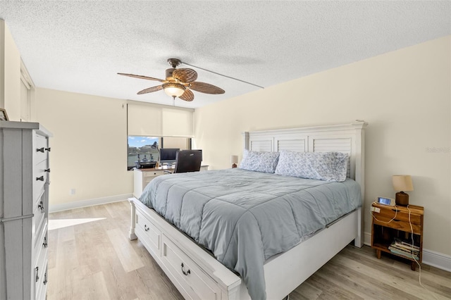 bedroom featuring a ceiling fan, light wood-type flooring, a textured ceiling, and baseboards