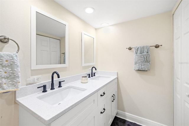 full bath featuring double vanity, a closet, baseboards, and a sink