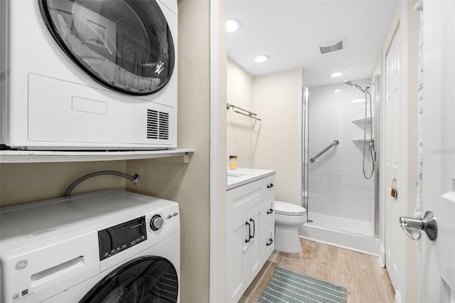 full bath with visible vents, a stall shower, stacked washer / dryer, vanity, and wood finished floors