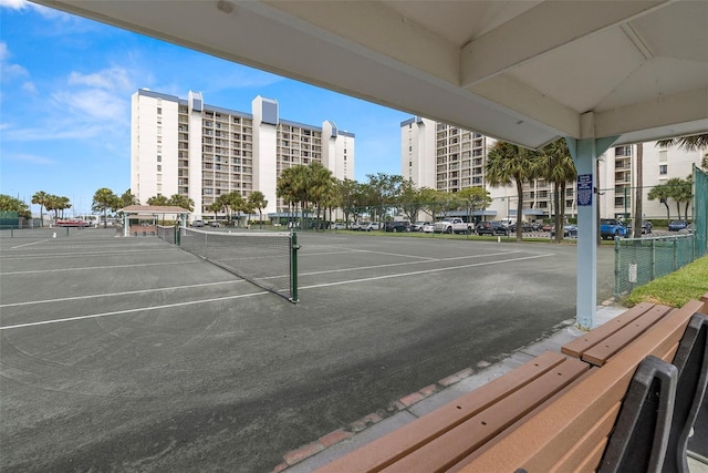 view of tennis court featuring fence and a city view