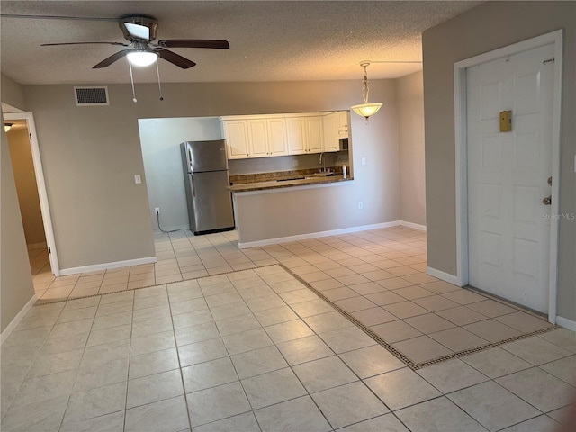 kitchen featuring light tile patterned floors, visible vents, hanging light fixtures, freestanding refrigerator, and white cabinetry