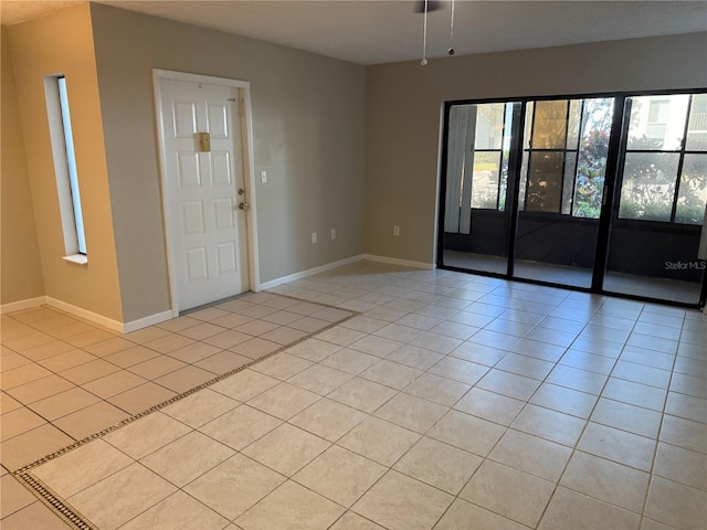 spare room featuring light tile patterned floors and baseboards