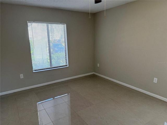 unfurnished room with a textured ceiling and baseboards