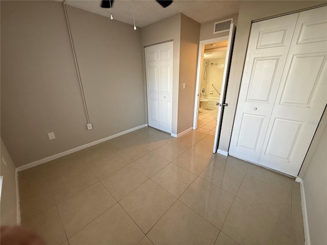 unfurnished bedroom with multiple closets, visible vents, baseboards, and light tile patterned floors