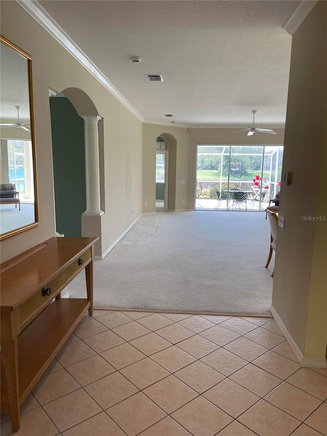 unfurnished room with ornamental molding, arched walkways, a ceiling fan, and light colored carpet