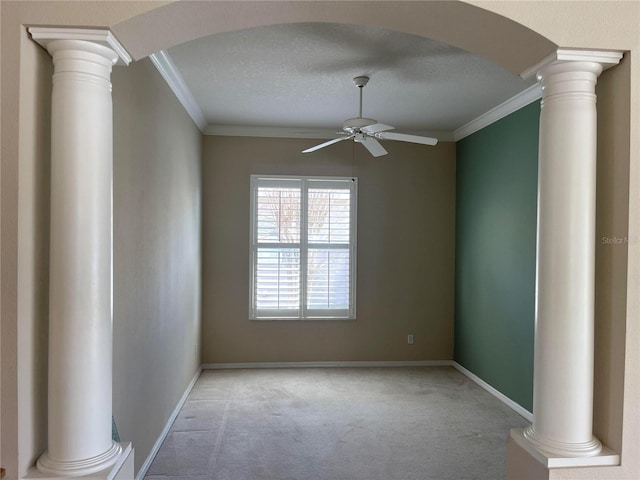 carpeted spare room featuring decorative columns, arched walkways, and crown molding