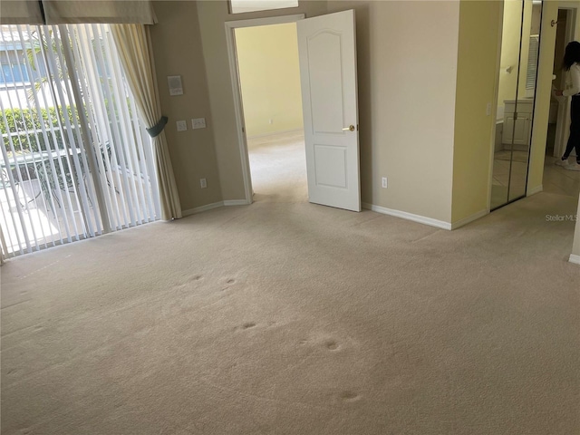 unfurnished room featuring baseboards and light colored carpet