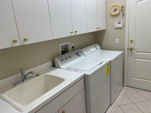 laundry area featuring cabinet space, light tile patterned floors, separate washer and dryer, and a sink