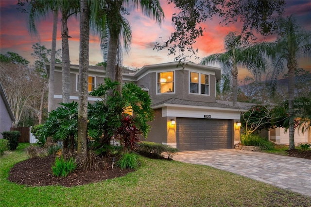 view of front of home with a garage, decorative driveway, a yard, and stucco siding