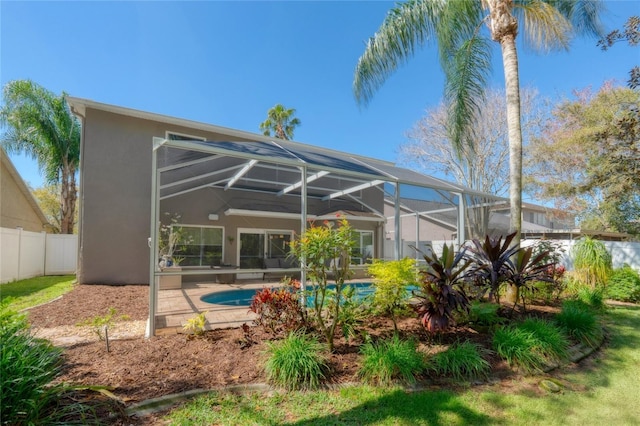 rear view of house featuring a fenced in pool, a lanai, fence, and stucco siding