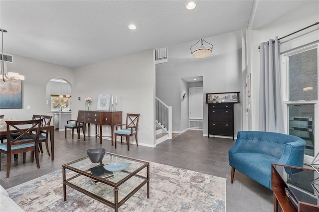 living room with arched walkways, recessed lighting, stairway, a textured ceiling, and baseboards