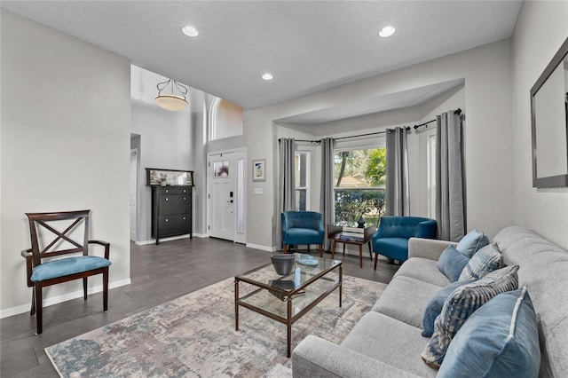 living area featuring baseboards, a textured ceiling, and recessed lighting