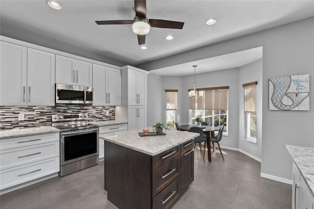 kitchen with baseboards, white cabinets, appliances with stainless steel finishes, decorative backsplash, and decorative light fixtures