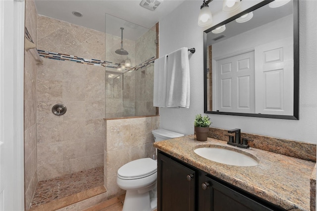 bathroom with visible vents, vanity, toilet, and walk in shower