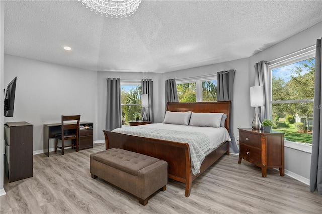 bedroom featuring light wood finished floors, baseboards, and a textured ceiling