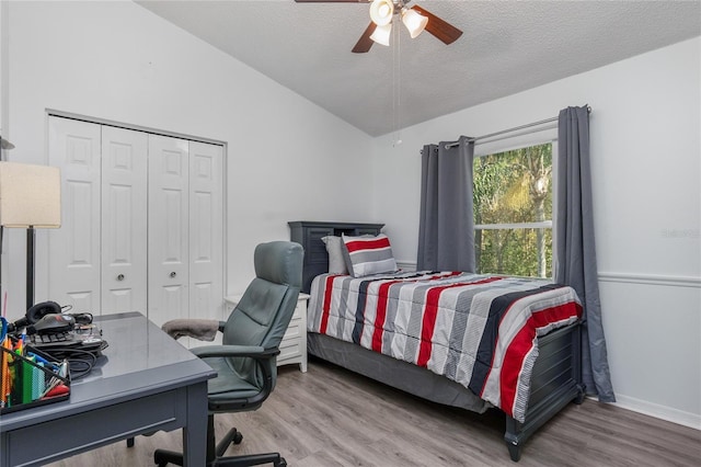 bedroom featuring lofted ceiling, a closet, a ceiling fan, a textured ceiling, and wood finished floors