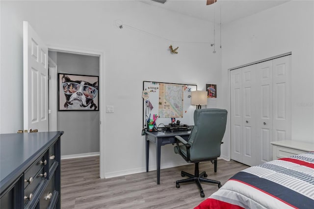 bedroom featuring light wood-style floors, ceiling fan, baseboards, and a closet