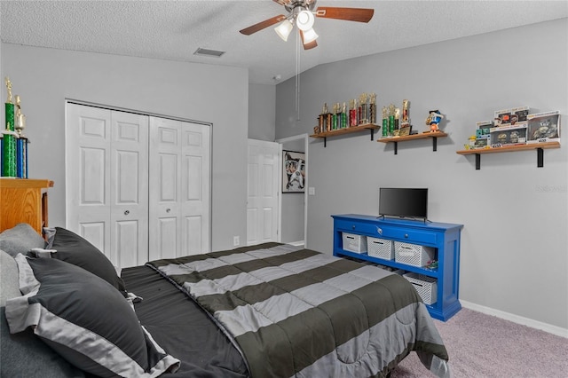 carpeted bedroom featuring a closet, vaulted ceiling, a textured ceiling, ceiling fan, and baseboards