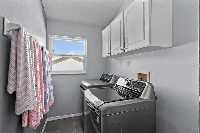 laundry area with dark tile patterned flooring, cabinet space, a textured ceiling, washer and dryer, and baseboards