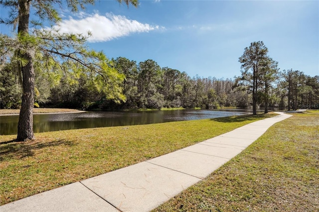 surrounding community with a lawn, a water view, and a view of trees