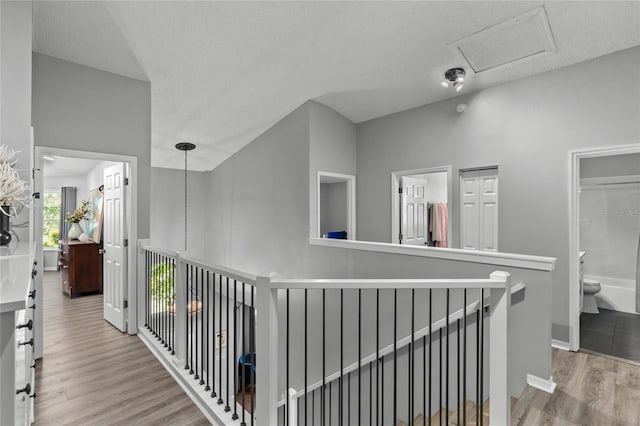 hallway featuring wood finished floors, an upstairs landing, and baseboards