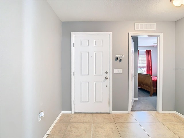 foyer entrance featuring visible vents, a textured ceiling, baseboards, and light tile patterned floors