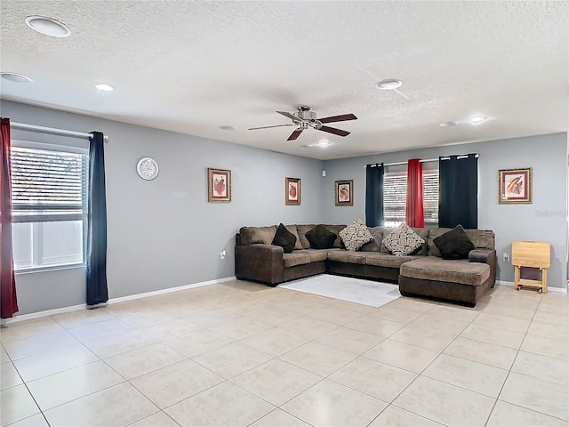 living area with ceiling fan, a textured ceiling, baseboards, and light tile patterned floors