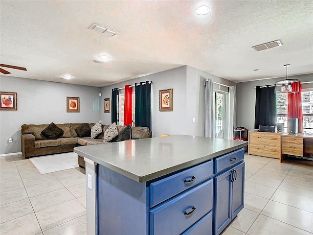 kitchen featuring visible vents, a kitchen island, open floor plan, blue cabinets, and pendant lighting